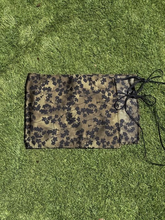 Green with black floral skirt laying flat on grass background