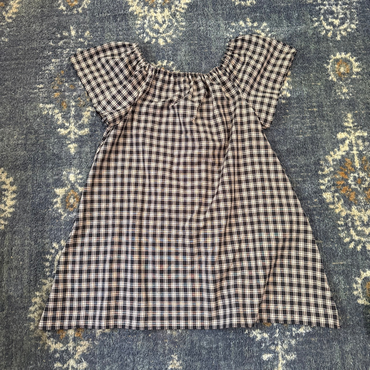 Black and white plaid dress on a blue rug.