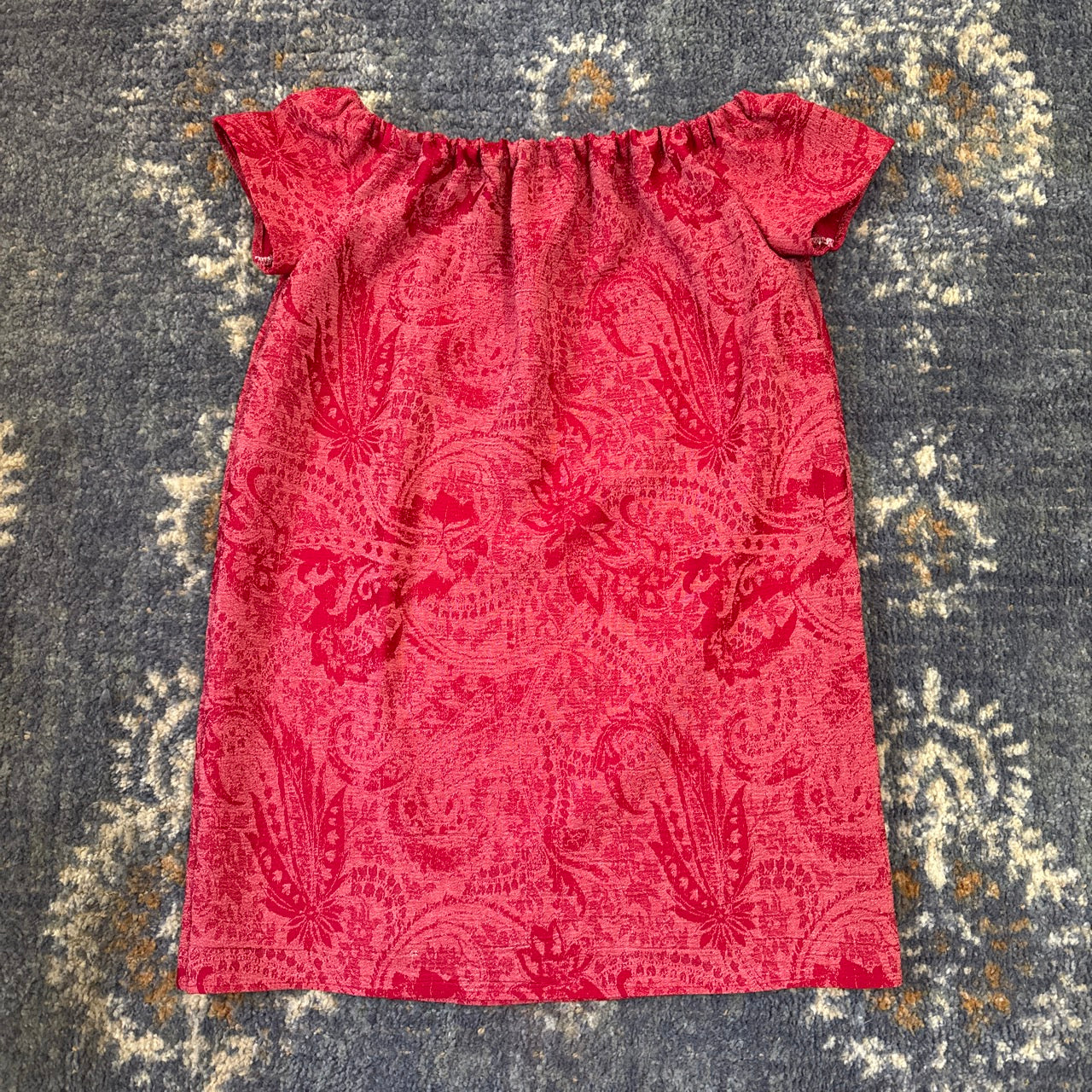 Red patterned dress on blue rug.