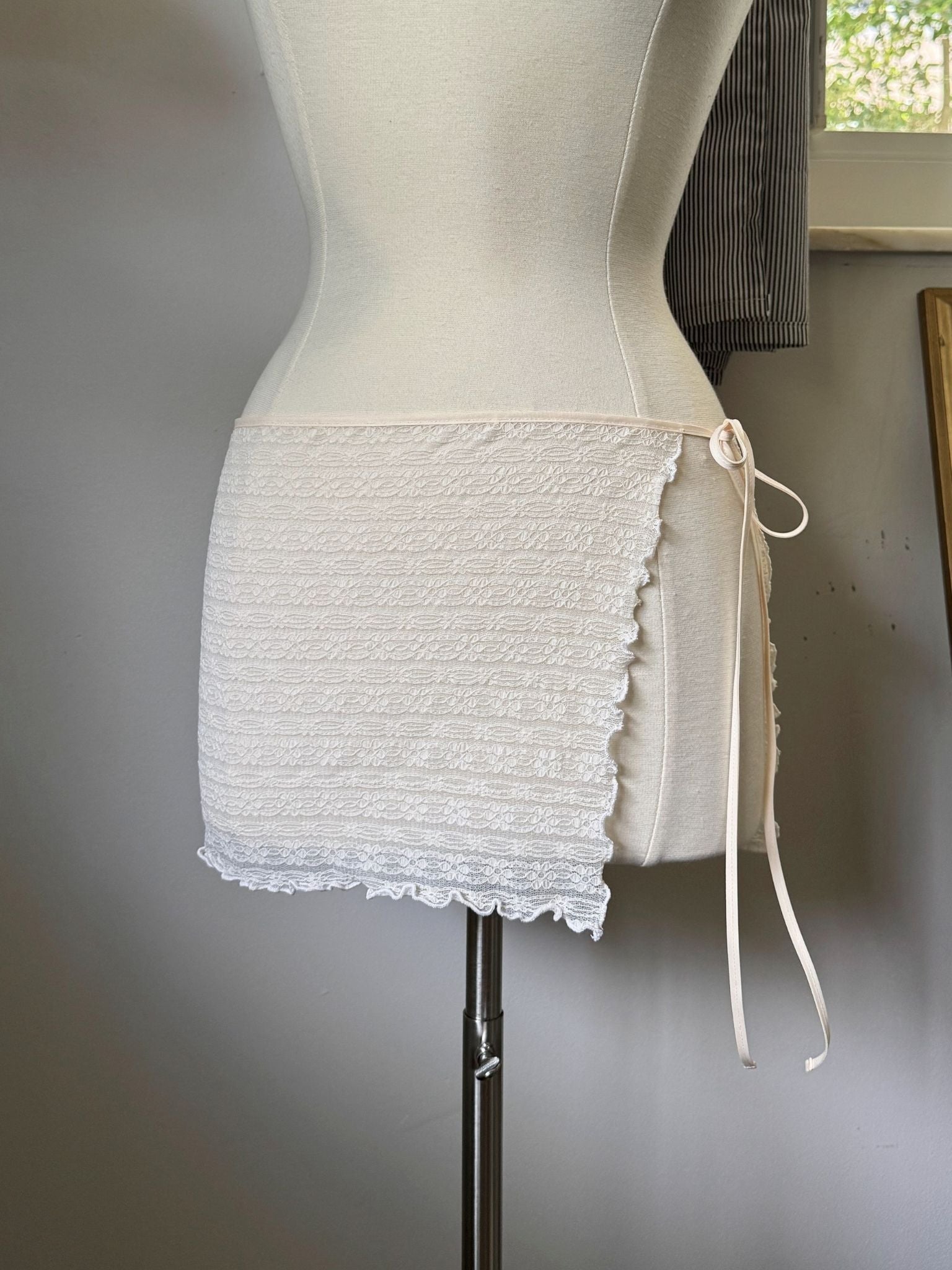 Mannequin wearing a textured white skirt with a plain background