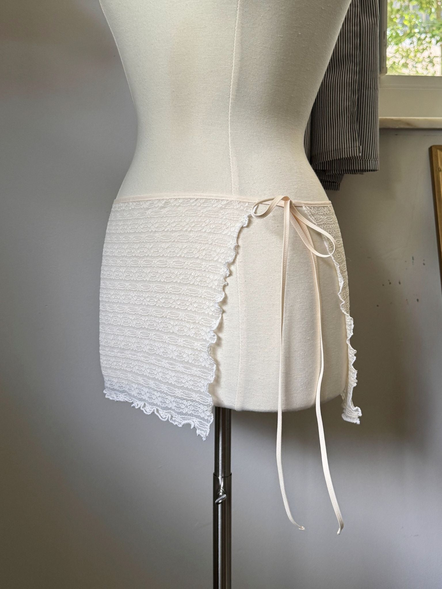 White lace skirt on a mannequin against a neutral background