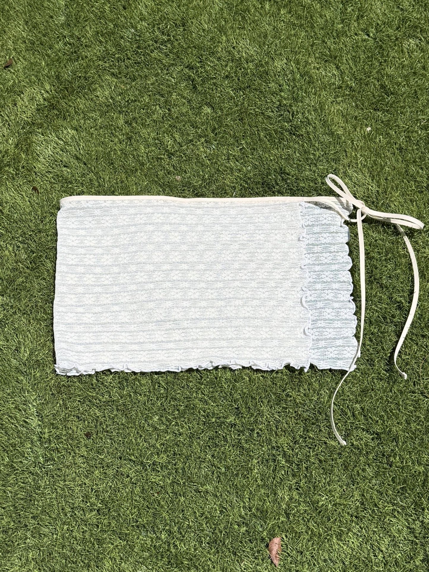 White lace skirt laid flat on a green grass background