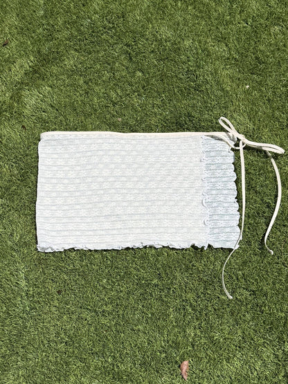 White lace skirt laid flat on a green grass background