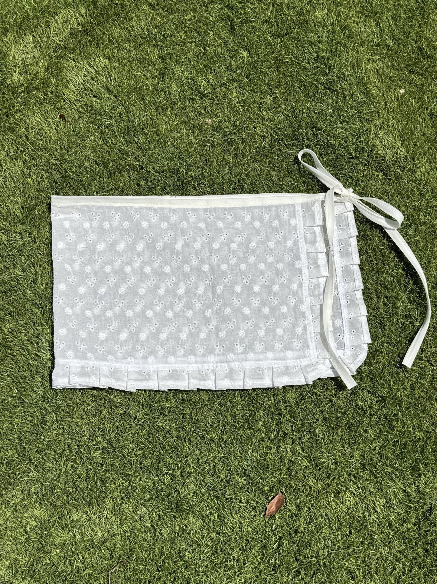 White skirt with floral embroidered florals and ruffles on a grassy background