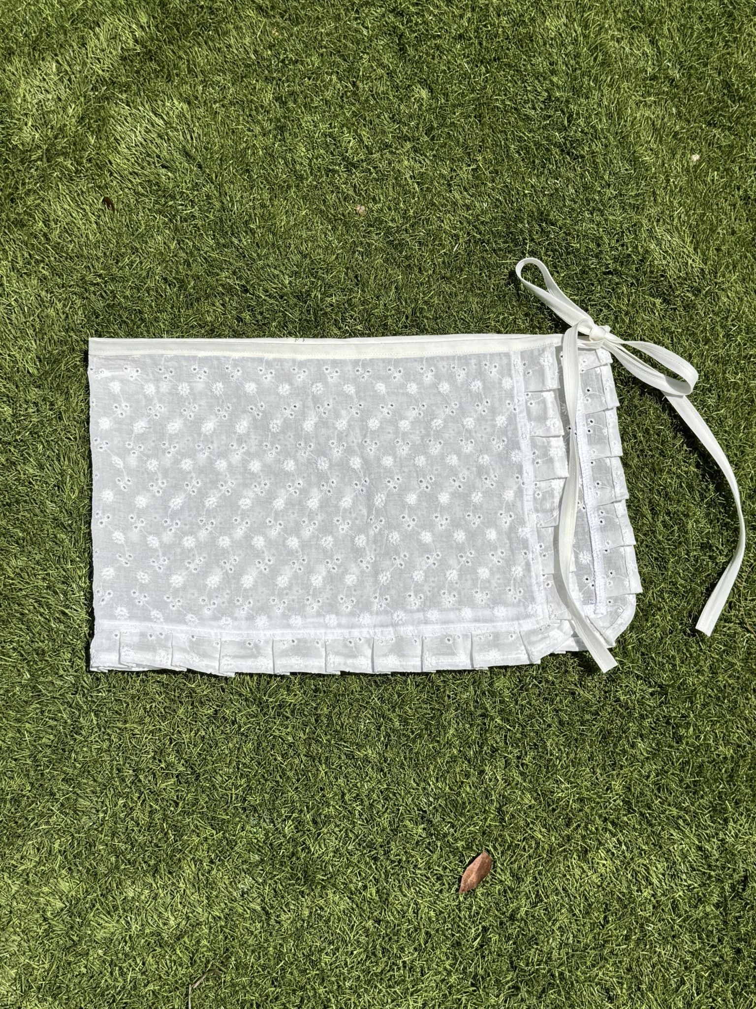 White skirt with floral embroidered florals and ruffles on a grassy background