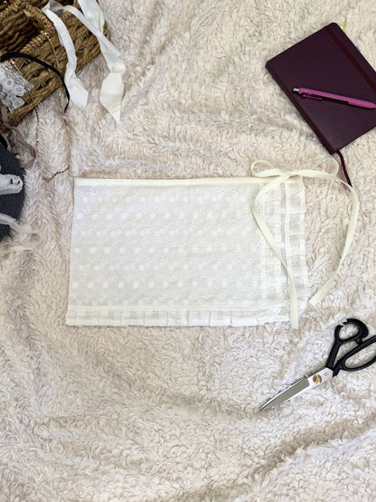 White fabric skirt with scissors, and a notebook on a textured surface