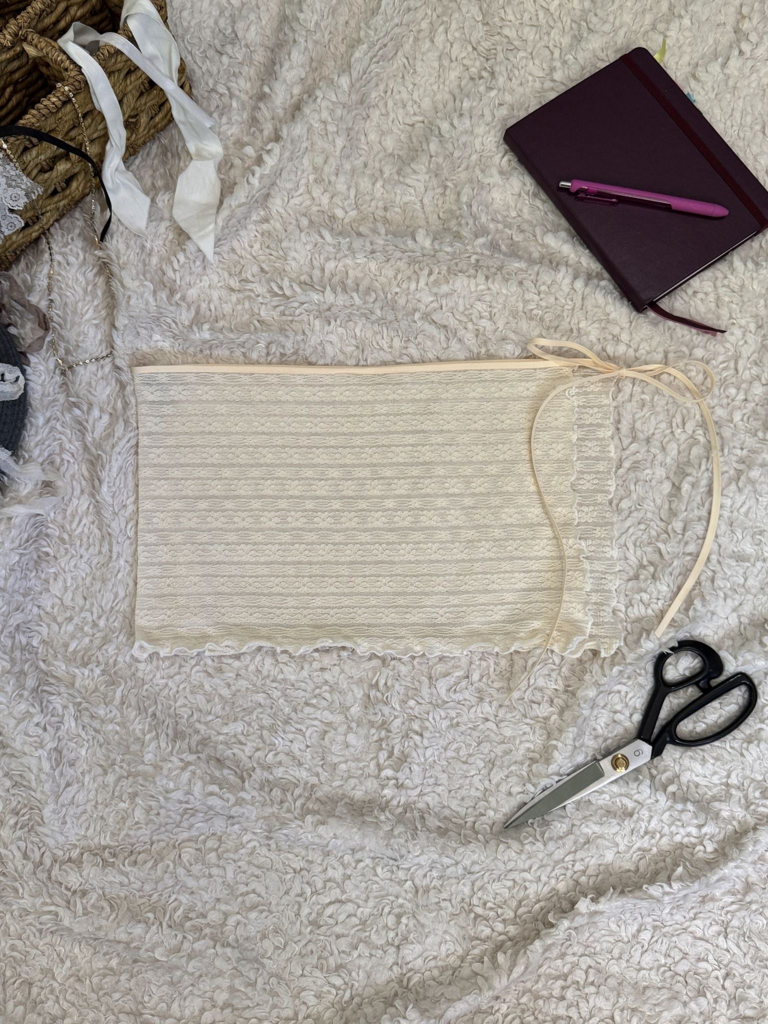 White lace skirt with scissors, and a notebook on a textured surface