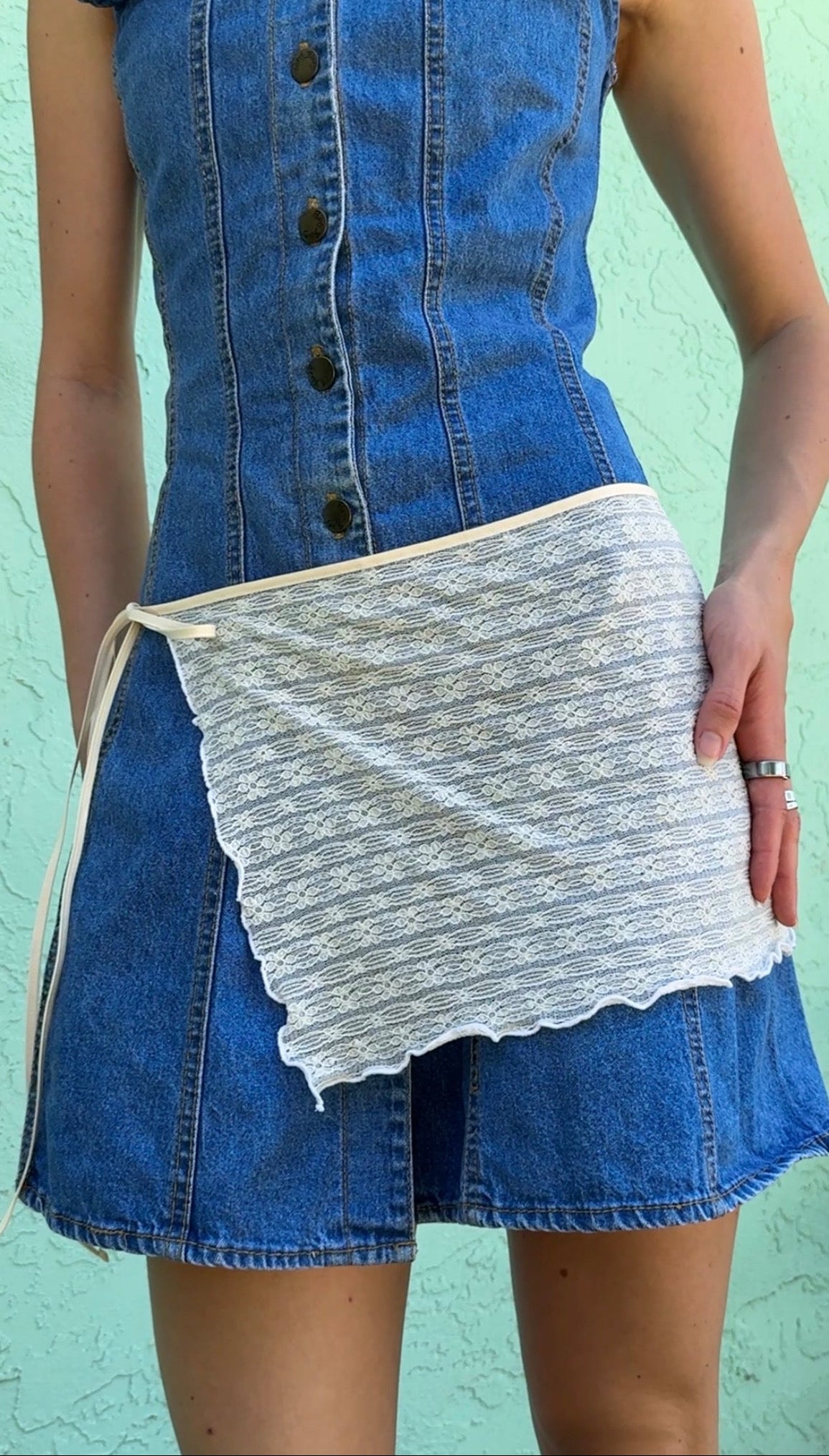 Blue denim dress with a white lace skirt against a light green background