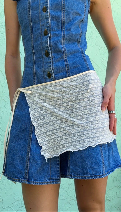 Blue denim dress with a white lace skirt against a light green background