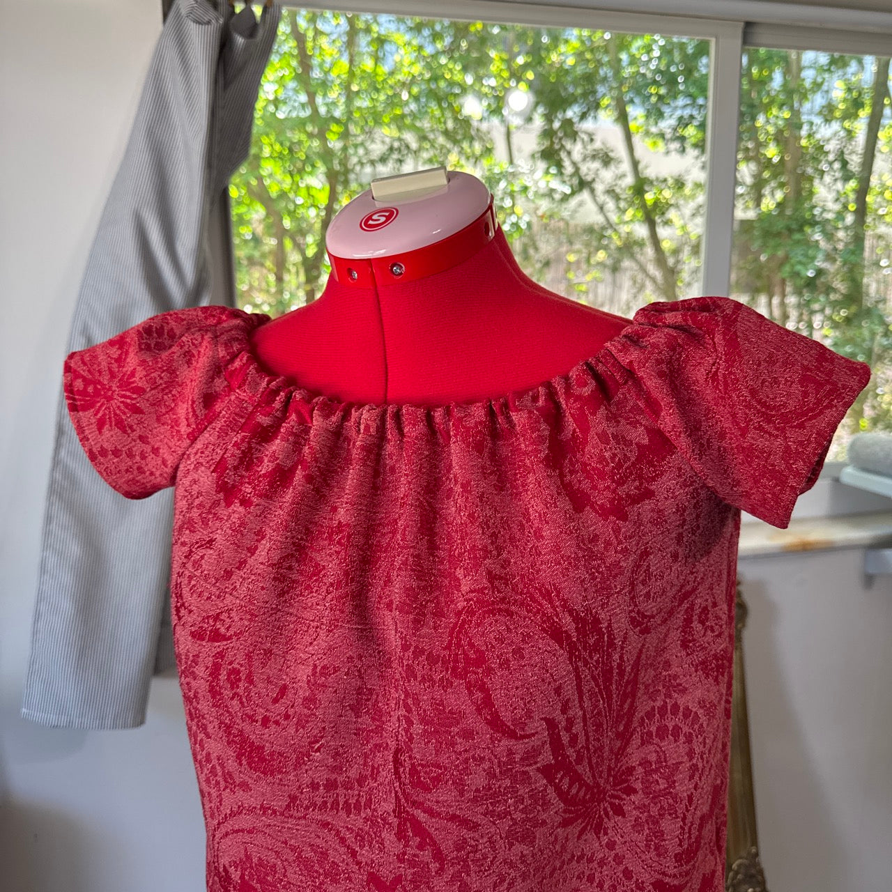Red patterned dress on a mannequin with a blurred indoor background