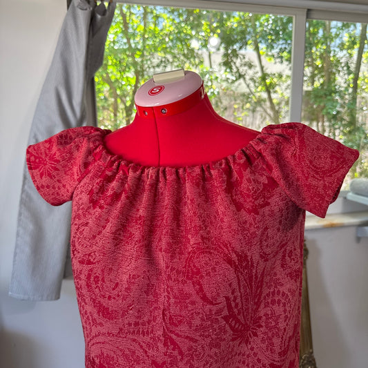 Red patterned dress on a mannequin with a blurred indoor background