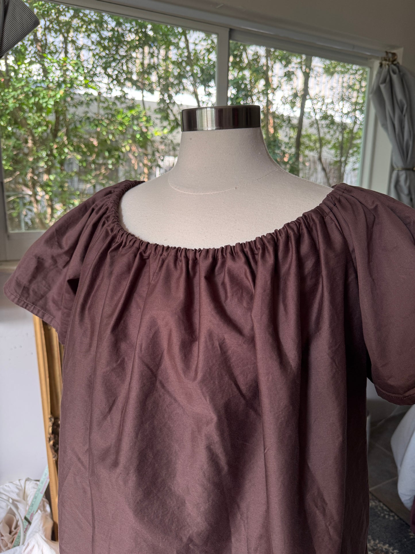 Brown off-shoulder top on a mannequin against a window background