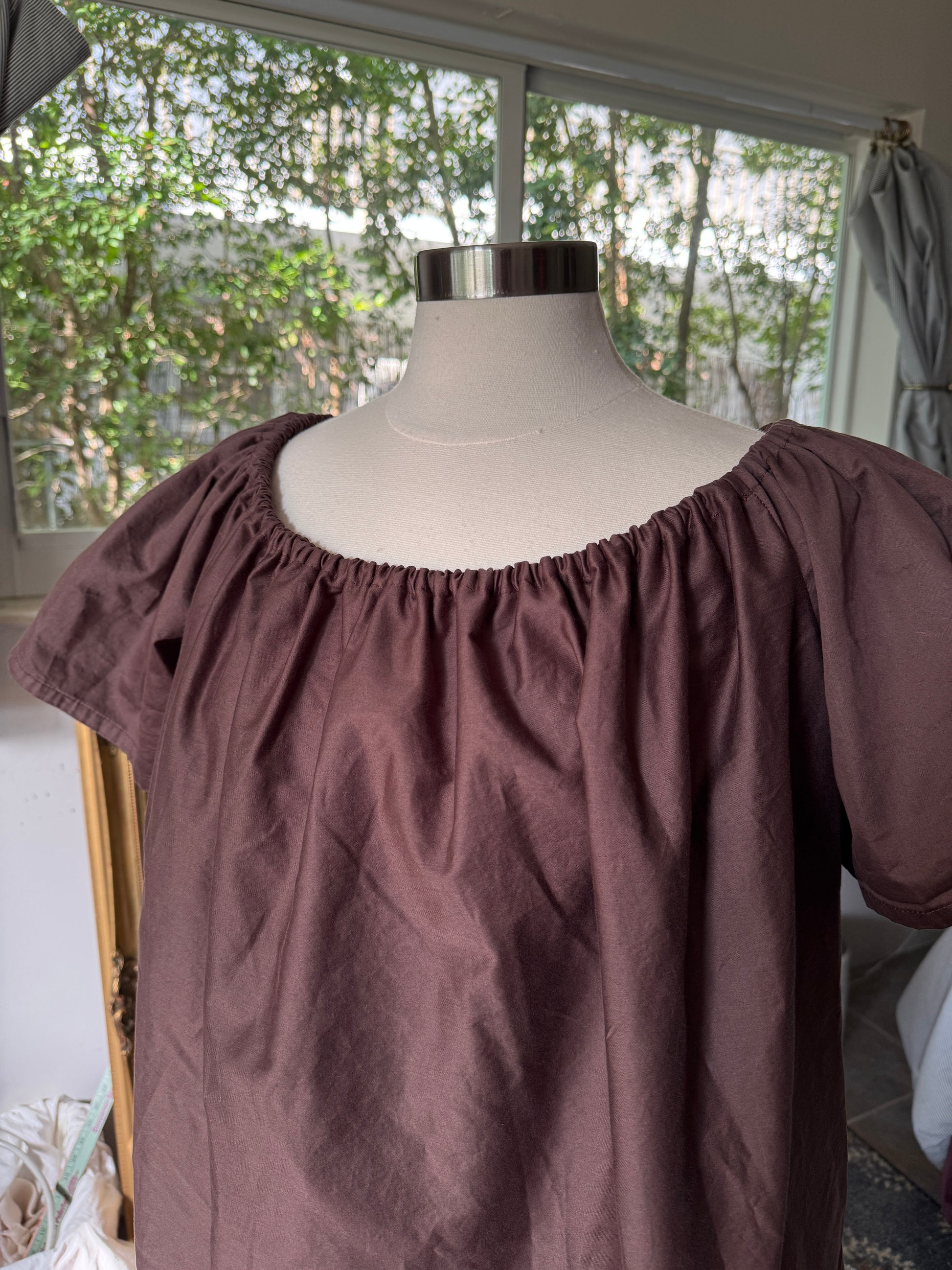 Brown off-shoulder top on a mannequin against a window background